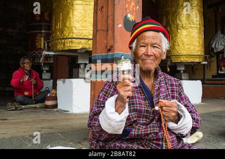 Bhutanischer alter Mann, der seinen Ruhestand in einem Kloster genießt und in Thimphu, Bhutan, im traditionellen Kleid buddhistisches Gebet praktiziert Stockfoto