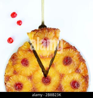 Gekürzter Ananas auf dem Kopf mit Glacé-Kirsche und Scapula auf weißem Hintergrund. Hausgemachtes Backen. Draufsicht. Stockfoto