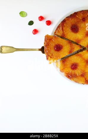 Gekürzter Ananas auf dem Kopf mit Glacé-Kirsche und Scapula auf weißem Hintergrund. Hausgemachtes Backen. Draufsicht. Stockfoto