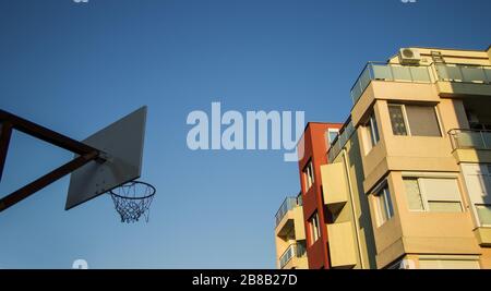 Low-Angle-Aufnahme eines Gebäudes neben einem Korb An einem Metallstange für Basketball befestigt Stockfoto