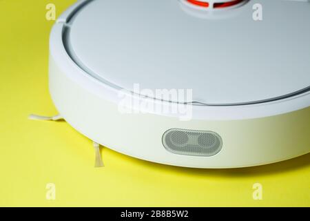 Weißer Roboter-Staubsauger zur Reinigung des Hauses auf gelbem Hintergrund Stockfoto