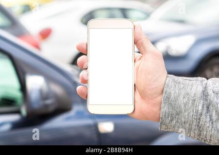 Mann hält Smartphone mit leerem weißen Bildschirm. Viele Autos oder Verkehr im Hintergrund. Handy in der Hand. Vorlage für Navigation oder Parken. Stockfoto