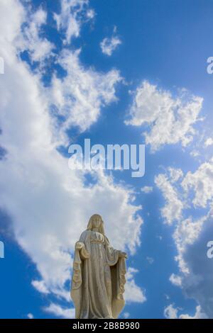 Statue der Jungfrau Maria mit wunderschönem Himmel mit Wolken im Hintergrund. Stockfoto
