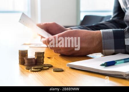 Mann liest Kontoauszug, Scheckerinnerung, Steuerrückerstattungsdokument, Telefonrechnung oder Finanzbrief. Preis- und Kostenkonzept für Heim- oder Krankenversicherung. Stockfoto