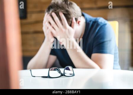 Konzept für Diskriminierung, Einsamkeit, psychische Gesundheit oder Depression. Trauriger verärgerter Mann, der Kopf oder Augen hält. Leiden unter Kopfschmerzen, Schlaflosigkeit oder Problemen. Stockfoto