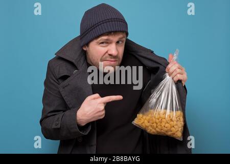Schmuggler verkauft Lebensmittel. Händler in Hut und Mantel zum Kauf von Pasta. Lebensmitteldefizit wegen Panik. Studio gedreht Stockfoto