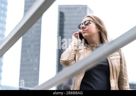 Frustrierte Frau, die in der Stadt telefoniert. Verärgerte oder ernste Dame mit Smartphone, die Stress hat. Stockfoto