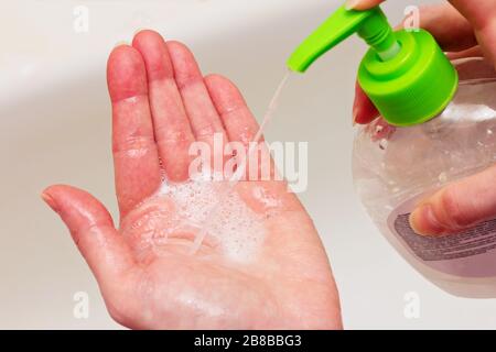 Eine Frau behandelt ihre Hände mit einem Antiseptikum mit einem Spender. Stockfoto