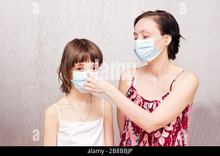Mutter und Tochter mit medizinischen Schutzmasken auf den Gesichtern. Stockfoto