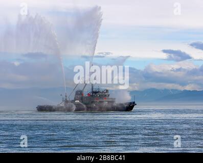 Das schwimmende Schleppboot sprüht Wasserstrahlen Stockfoto