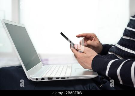 Ein Mann mittleren Alters, der sich zu Hause beiläufig anzog und mit einem Computer von zu Hause aus arbeitet. Stockfoto