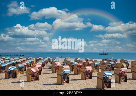 Ein Panorama-Foto mit bunten liegen am Strand bei schönem Wetter und einem Regenbogen Stockfoto