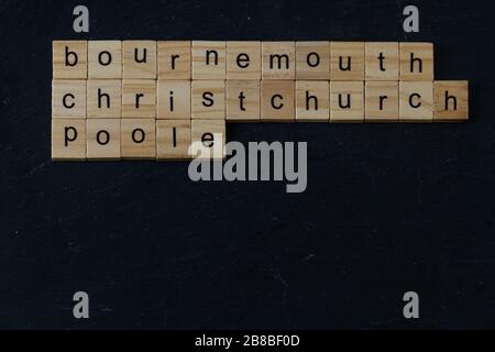Bournemouth Christchurch Poole buchstabierte in Holzblöcken auf dunklem Schiefergrund. Copyspace, Querformat Stockfoto
