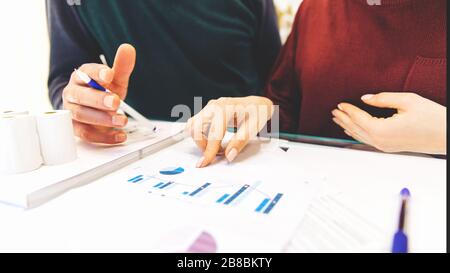 Frau und Mann arbeiten zu Hause, arbeiten zu Hause, mit Laptop und Notizblock, machen sich Notizen auf dem Telefon, zählt auf einem Rechner. Nahaufnahme von Buchhalterin oder Bankerin, die Berechnungen durchführt. Sparkonzept, Finanzen und Sparkonzept Stockfoto