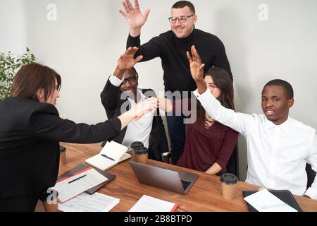 Junge glückliche Geschäftsleute arbeiten in modernen Büros und multiethnischen Teamarbeit zusammen. Geschäftspartner, die sich bei der Besprechung einen Haufen Hände anhäufen Stockfoto