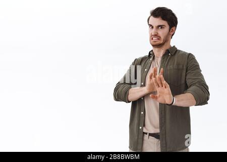 Angeekelter widerwärtiger bärtiger Mann, der sich vor der Abneigung trauert, sich entsetzt abwendet, etwas schreckliches vermeidet, die Hände im Stopp hochhebt, keine oder Verbotsgeste Stockfoto