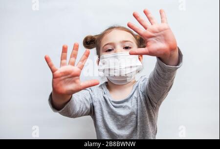 Kleine Mädchen in einer Einwegmaske zeigt ihre Hände. Epidemischer Schutz durch Coronavirus Stockfoto