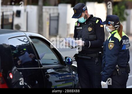 Vendrell, Spanien. März 2020. Ein Polizeibeamter, der eine Gesichtsmaske und chirurgische Handschuhe als Vorsichtsmaßnahme gegen die Verbreitung von Coronavirus an einem Polizeikontrollpunkt trägt, überprüft ein Fahrzeug, das er zuvor angehalten hatte.die örtliche Polizei in El Vendrell verhindert, dass Menschen aus anderen Städten zu ihrer Wohnung im Strandbereich kommen, um dies zu verhindern Die Ausbreitung des Covid-19-Coronavirus. El Vendrell ist eine Stadt, die mit der Ankunft der Wochenenden im Frühling und Sommer ihre Bevölkerung durch die Wohnungen im Strandbereich verdoppelt, die im Besitz von Menschen aus anderen Städten sind. Credit: SOPA Images Limited/Alamy Live News Stockfoto