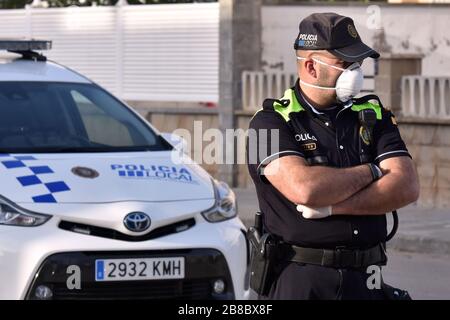 Vendrell, Spanien. März 2020. Ein Polizeibeamter, der eine Gesichtsmaske und chirurgische Handschuhe als Vorsichtsmaßnahme gegen die Ausbreitung von Coronavirus trägt, steht an einem Polizeikontrollpunkt.die örtliche Polizei in El Vendrell verhindert, dass Menschen aus anderen Städten zu ihrer Wohnung im Strandbereich kommen, um die Ausbreitung des Covid-19 Coronavirus zu verhindern. El Vendrell ist eine Stadt, die mit der Ankunft der Wochenenden im Frühling und Sommer ihre Bevölkerung durch die Wohnungen im Strandbereich verdoppelt, die im Besitz von Menschen aus anderen Städten sind. Credit: SOPA Images Limited/Alamy Live News Stockfoto