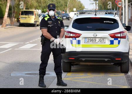 Vendrell, Spanien. März 2020. Ein Polizeibeamter, der eine Gesichtsmaske und chirurgische Handschuhe als Vorsichtsmaßnahme gegen die Ausbreitung von Coronavirus trägt, steht an einem Polizeikontrollpunkt.die örtliche Polizei in El Vendrell verhindert, dass Menschen aus anderen Städten zu ihrer Wohnung im Strandbereich kommen, um die Ausbreitung des Covid-19 Coronavirus zu verhindern. El Vendrell ist eine Stadt, die mit der Ankunft der Wochenenden im Frühling und Sommer ihre Bevölkerung durch die Wohnungen im Strandbereich verdoppelt, die im Besitz von Menschen aus anderen Städten sind. Credit: SOPA Images Limited/Alamy Live News Stockfoto