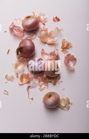 Viele rote Zwiebeln, mit Zwiebelschälchen auf weißem Hintergrund Stockfoto