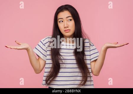 Antwort nicht bekannt! Porträt eines verwirrten Mädchens ohne Ahnung mit langen Haaren in gestreiftem T-Shirt, das die Hände in verwirrender, verwirrter mit Frage verwirrt, mit d Stockfoto