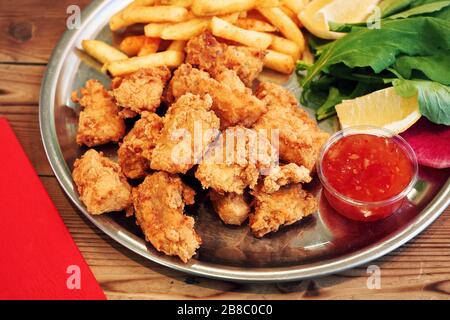 Frittierte Muscheln in einem Teller mit Sauce und pommes frites auf einem Holz-Restauranttisch Stockfoto