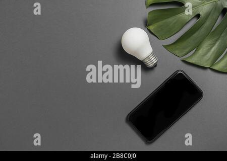 Top View flacher Lay von Kreativität Inspiration, Ideen Konzepte mit Glühlampe, Green Leaf Monstera und modernes Smartphone, Mockup Komposition mit Kopie s Stockfoto