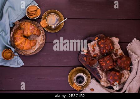 Brownie, Chocolate Cakes mit Mandeln auf einem Holzbrett und Croissant, mit Kakao bestreut. Serviert werden hausgemachte Kuchen. Draufsicht. Freier Speicherplatz für Text. Stockfoto