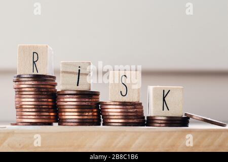 Holzwürfel mit dem Wort Risiko und Münzhaufen, Geldtreppen. Geschäftskonzept Stockfoto