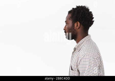 Profilschuss afroamerikanischer bärtiger Mann mit lockig kurzen Haaren über weißem Hintergrund mit lockerem, ruhigem Ausdruck, links leer aussehend Stockfoto