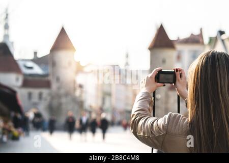 Frau in Tallinn fotografieren Viru-Tor. Touristen im Urlaub, die ein Bild vom Wahrzeichen Estlands machen. Menschen, die in einer beliebten Straße spazieren gehen. Stockfoto