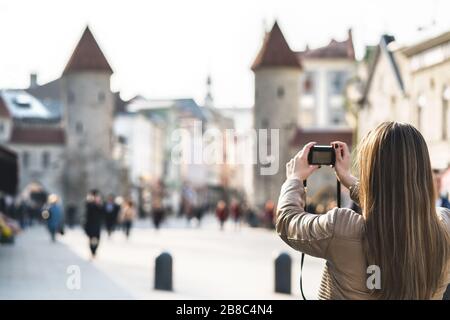 Tourist in Tallinn Foto von Viru-Tor. Frau im Urlaub, die sich ein Bild vom Wahrzeichen Estlands machen kann. Menschen, die in einer beliebten Straße spazieren gehen. Stockfoto