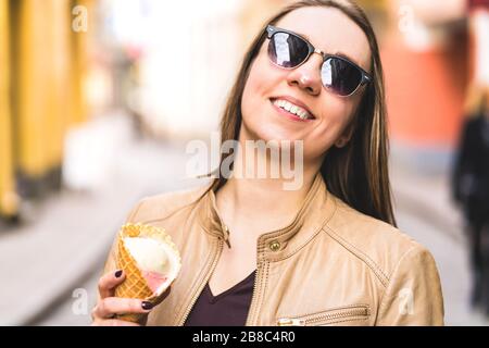 Frau mit geschmolzenem Eis an der Nase. Fröhliche lächelnde Person, die schmelzende Eiscreme in der Stadt isst. Unordentliches Gesicht. Stockfoto