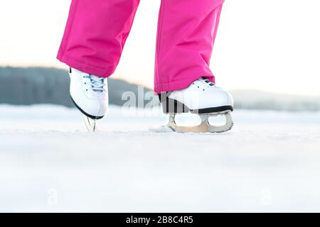 Mädchen Schlittschuhlaufen auf Eis im Freien. Skater auf gefrorenem See oder Teich. Junge Frau kickend. Eiskunstlaufübung oder -Training. Winterspaß im Winter. Stockfoto