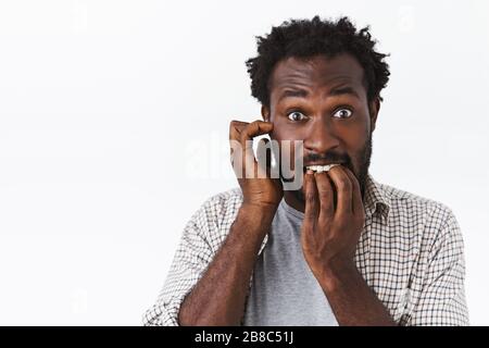 Peinlich und besorgt bärtiger afro-amerikanischer Kerl fühlen sich in Panik, beißende Nägel und kratzende Ohren, starrende Kameraforsch, Fehler oder Fehler machen, gegenüberstehen Stockfoto