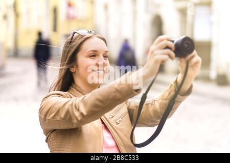 Frau fotografiert im Urlaub. Fröhliche Reisende, die Fotos mit Digitalkamera machen. Touristen in der Altstadt in Europa. Stockfoto