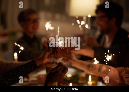 Eine Gruppe junger Leute, die am Tisch sitzen und glitzern und während der Party Spaß haben Stockfoto