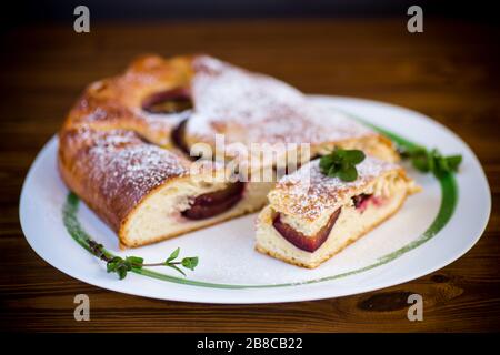 Süß gebackener hausgemachter Pflaumenkuchen mit Puderzucker auf einem Holztisch Stockfoto