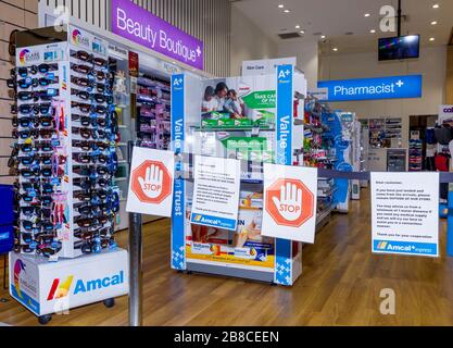 Coronavirus Warnschilder und Sicherheitsbarrieren in einer Amcal Apotheke am internationalen Abflugterminal des Flughafens Sydney (Kingsford Smith) in Australien. Der Chemiker hatte die Barriere und Warnungen am Ladeneingang platziert, um Flugpassagiere, die gerade nach Australien gekommen waren, zu bitten, sich an "soziale Distanzierungsregeln" zu halten, um das Risiko einer Verbreitung des Coronavirus zu verringern. Stockfoto