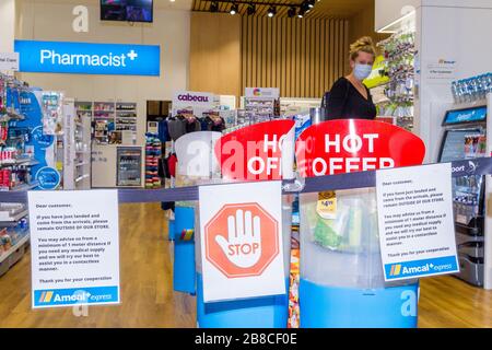 Coronavirus Warnschilder und Sicherheitsbarrieren in einer Amcal Apotheke am internationalen Abflugterminal des Flughafens Sydney (Kingsford Smith) in Australien. Der Chemiker hatte die Barriere und Warnungen am Ladeneingang platziert, um Flugpassagiere, die gerade nach Australien gekommen waren, zu bitten, sich an "soziale Distanzierungsregeln" zu halten, um das Risiko einer Verbreitung des Coronavirus zu verringern. Stockfoto