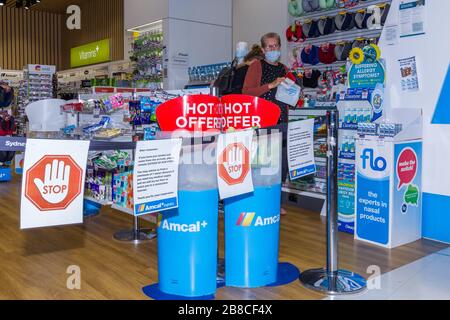 Coronavirus Warnschilder und Sicherheitsbarrieren in einer Amcal Apotheke am internationalen Abflugterminal des Flughafens Sydney (Kingsford Smith) in Australien. Der Chemiker hatte die Barriere und Warnungen am Ladeneingang platziert, um Flugpassagiere, die gerade nach Australien gekommen waren, zu bitten, sich an "soziale Distanzierungsregeln" zu halten, um das Risiko einer Verbreitung des Coronavirus zu verringern. Stockfoto