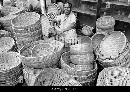 Eine alte Frau machte Handwerksprodukte und den Bambuskorb für den Verkauf an den Kunden auf dem ländlichen Markt Indiens. Stockfoto