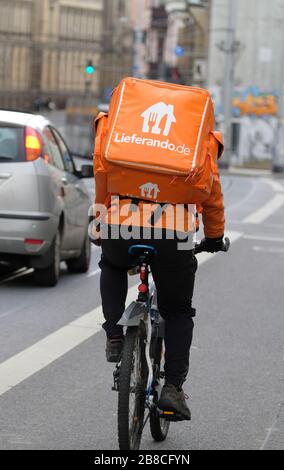 Leipzig, Deutschland. März 2020. Der Fahrer eines Lieferdienstes fährt mit seinem Fahrrad über eine Straße. Credit: Sebastian Willnow / dpa-Zentralbild / dpa / Alamy Live News Stockfoto