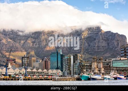 Docks, Lagerhäuser und Fischerboote des Table Bay Harbour bilden das Vorderstück zum Central Business District dahinter, alle dominiert vom Table Mountain Stockfoto