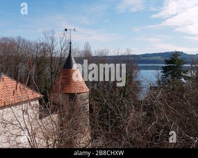 Rundturm mit Kegeldach und Wetterfahne des Enkeln Schlosses in der Schweiz. See Neuchâtel im Hintergrund. Stockfoto