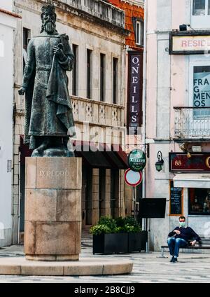 Cascais, Portugal - 21. März 2020: Statue von Don Pedro in Cascais in Portugal mit Mann, der Gesichtsmaske im Hintergrund während der Covid-19-Epidemie trägt Stockfoto