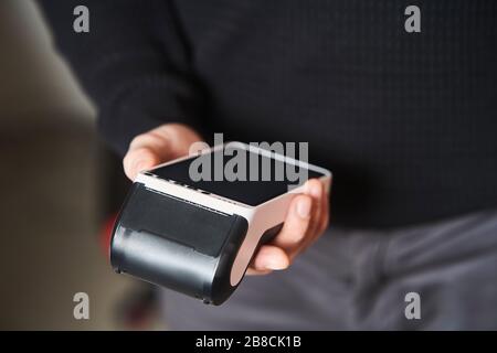 Bankterminal für kontaktlose Zahlung. Der junge Mann hält ein Terminal in seinen Händen Stockfoto