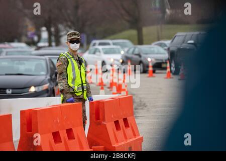 Paramus, NJ, USA. März 2020. Nationalgarde Der New Jersey Army Sgt. Albert Chu, Soldat bei der 508th Military Police Company, leitet den Verkehr an einem COVID-19-gemeinschaftsbasierten Teststandort am Bergen Community College in Paramus, New Jersey, am 20. März 2020. Der in Partnerschaft mit der Federal Emergency Management Agency (FEMA) eingerichtete Teststandort war mit dem Gesundheitsministerium von New Jersey, der Staatspolizei von New Jersey und der Nationalgarde von New Jersey besetzt. Das Drive-Thru-Testzentrum ist sieben Tage pro Woche geöffnet, von 8:00 Uhr bis 16:00 Uhr. Credit: UPI/Alamy Live News Stockfoto