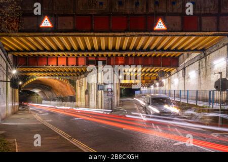 Vyne Road/Chapel Hill Eisenbahnbrücke E1/135A auf der Eisenbahnlinie BML1 in Basingstoke zur Nachtzeit. RBE Stahlträger- und Ziegelbogenkonstruktion. Stockfoto